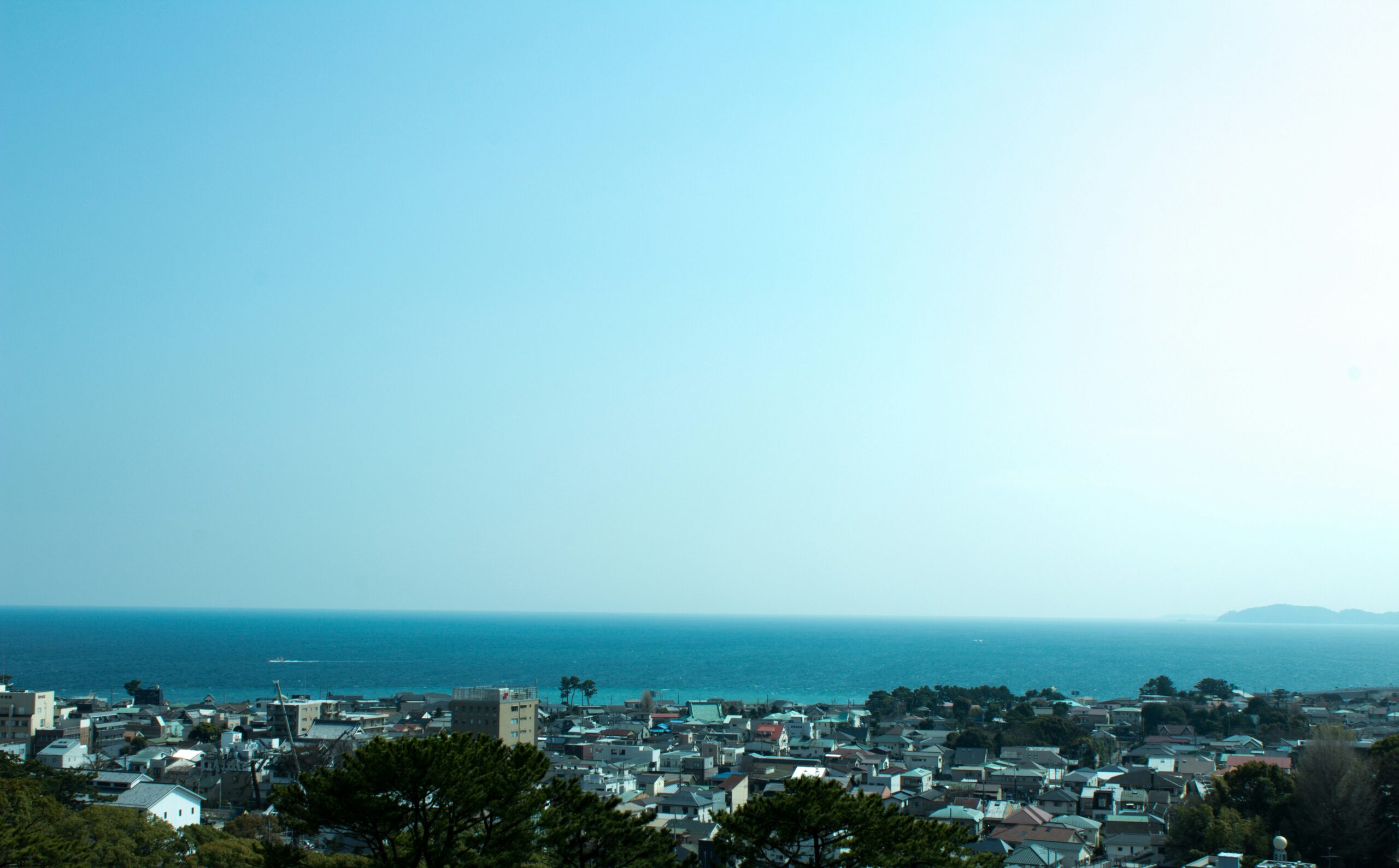 Panoramic view overlooking Sagami Bay, buildings are in the forefront and the blue bay is in the background with a view of mountains on the right