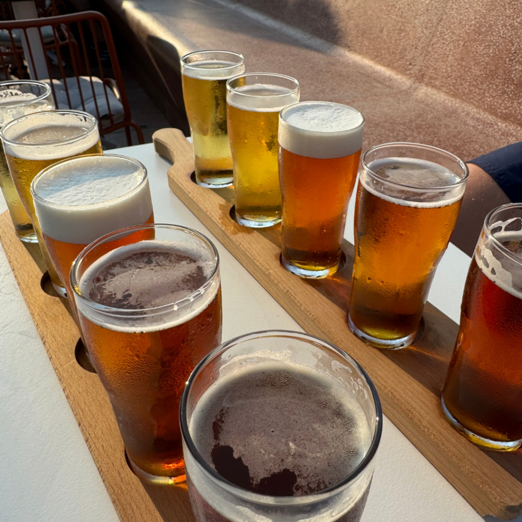 Flight of five beers on a board, all ranging in colours. All the same size, mini-pints. There are ten beers in total, two boards of five next to each other.