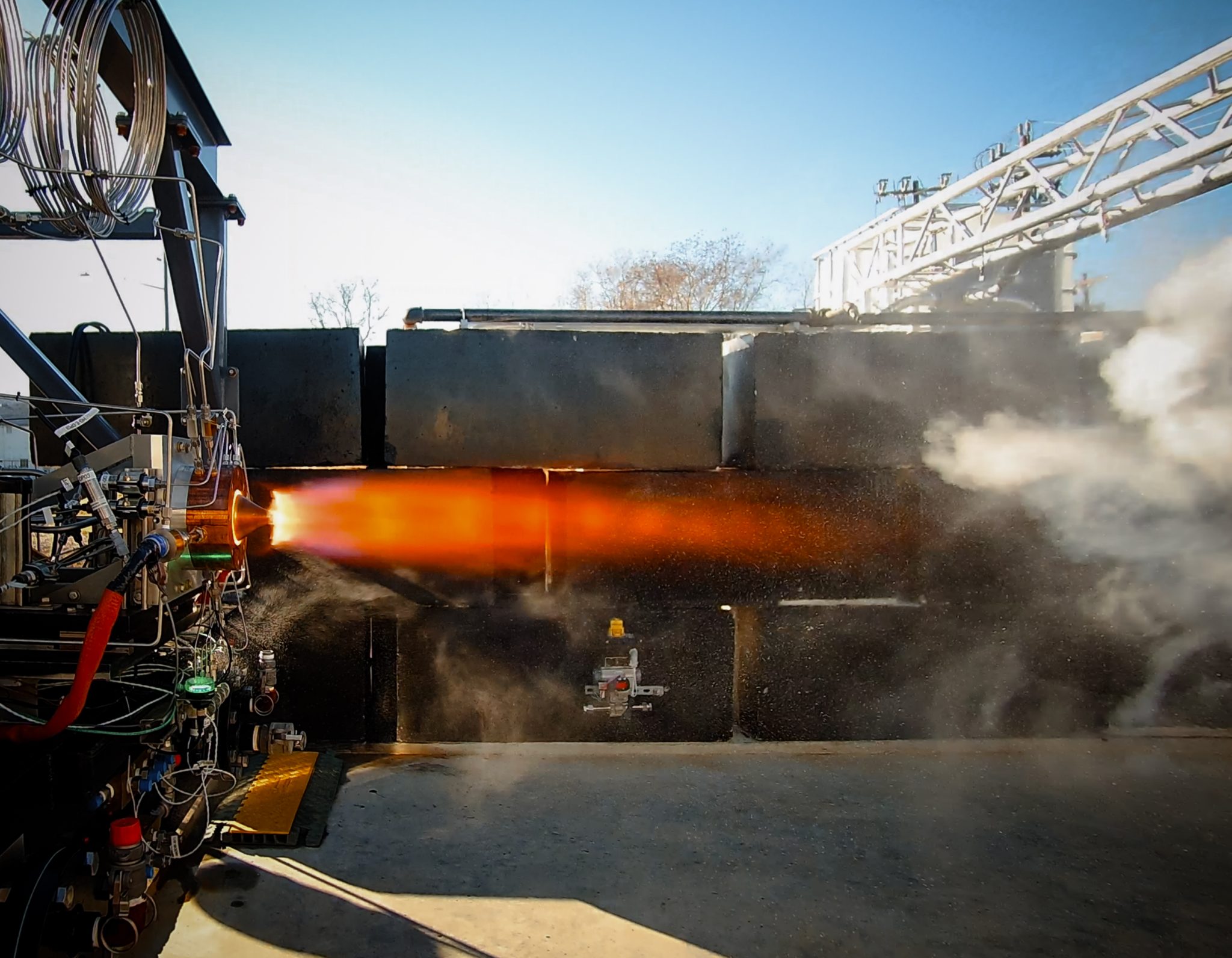 Venus Aerospace engine being fired, can see the flames and blue sky in the background.