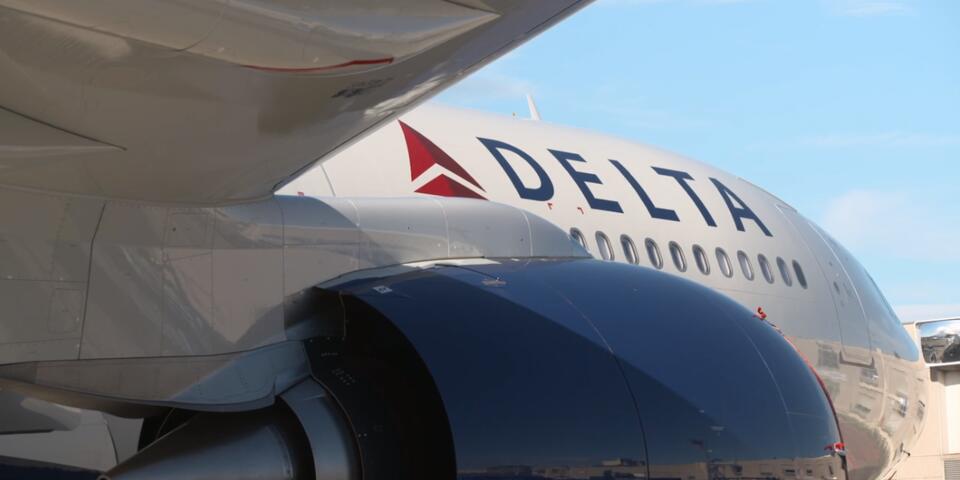 Sideshot of a Delta Airlines place, can see the tip and slightly underneath its wing.