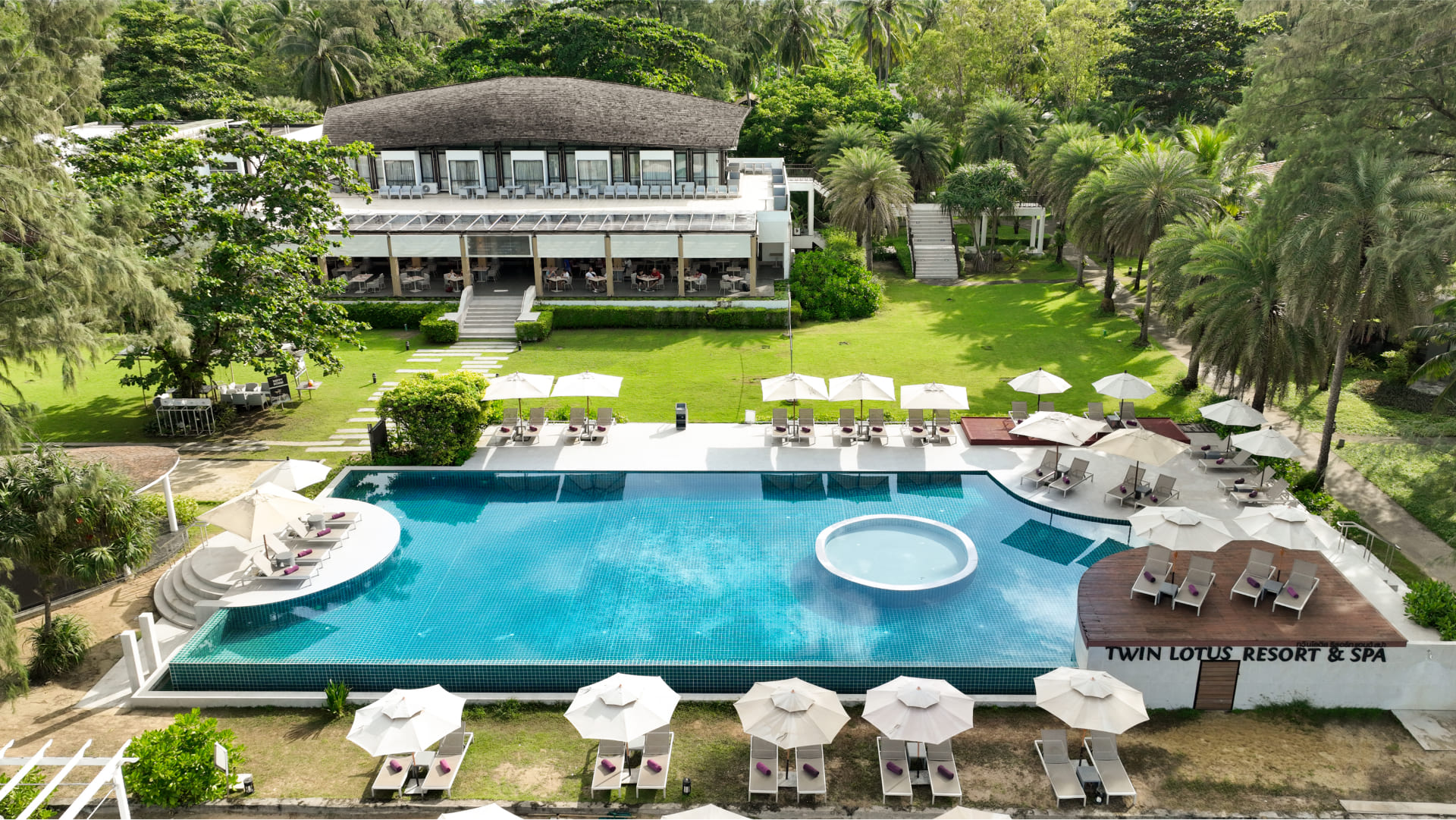 Twin Lotus Resort and spa in Koh Lanta, Thailand. Can see the infinity pool, sunbeds around it and a building in the back.