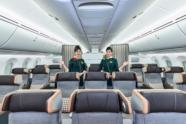 EVA Air plane inside Premium Economy, can see the chairs and two employees standing behind them smiling at the camera.