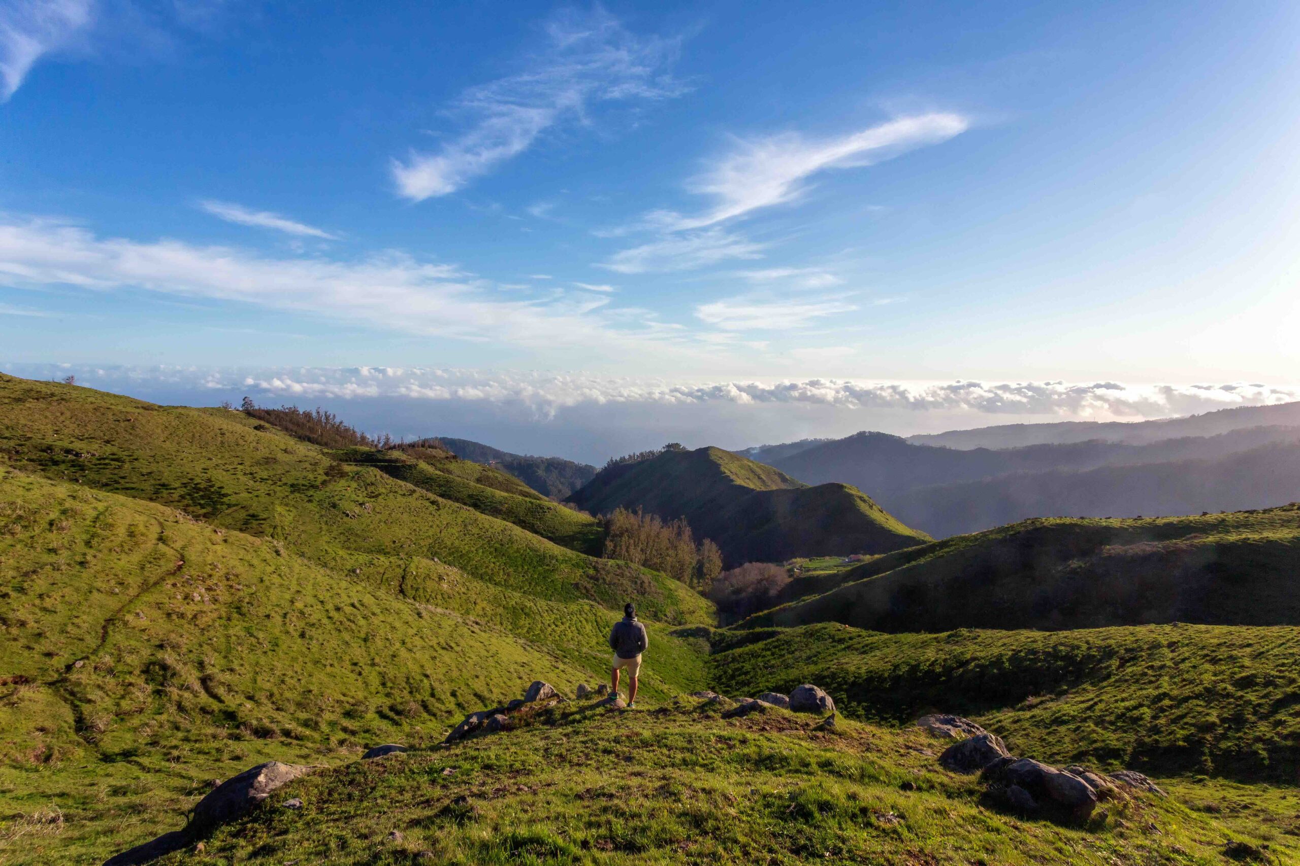 Person walking almost green landscape in Madeira, with blue skies.